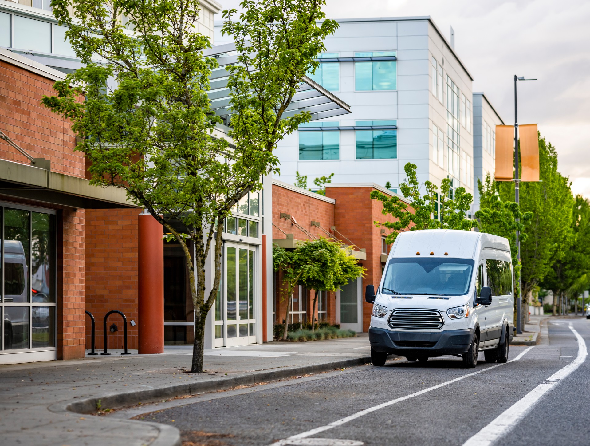 Compact commercial mini van standing on the urban city street with multilevel apartments buildings